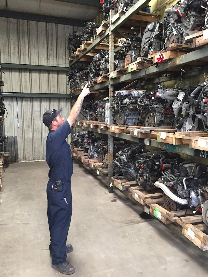 Worker inspecting parts in a recycling warehouse.