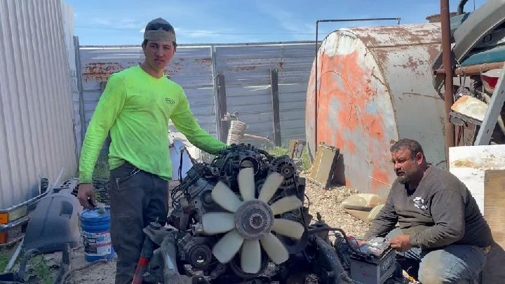 Workers handling an engine at Valley Auto Wreckers.