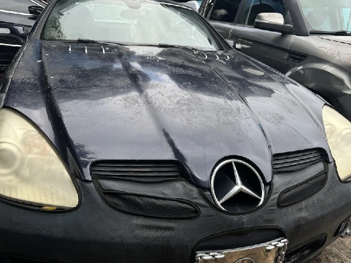 Abandoned black Mercedes in a junkyard.