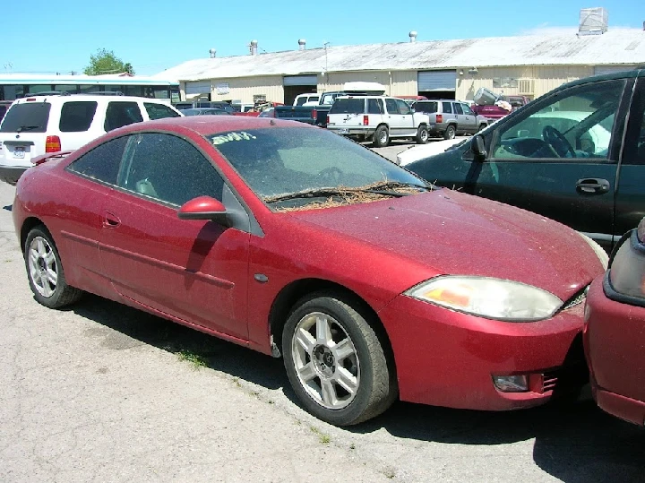 Abandoned red car in a junkyard. Dusty and damaged.