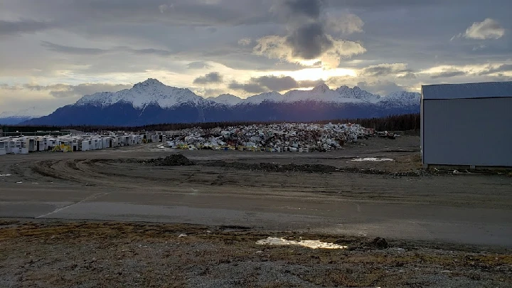 Alaska recycling yard with mountains in the background.