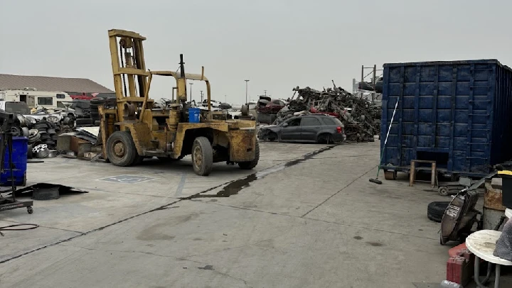 Auto salvage yard with a forklift and scrap cars.