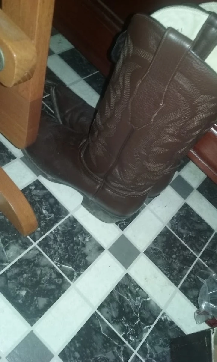 Brown cowboy boots on a checkered floor.