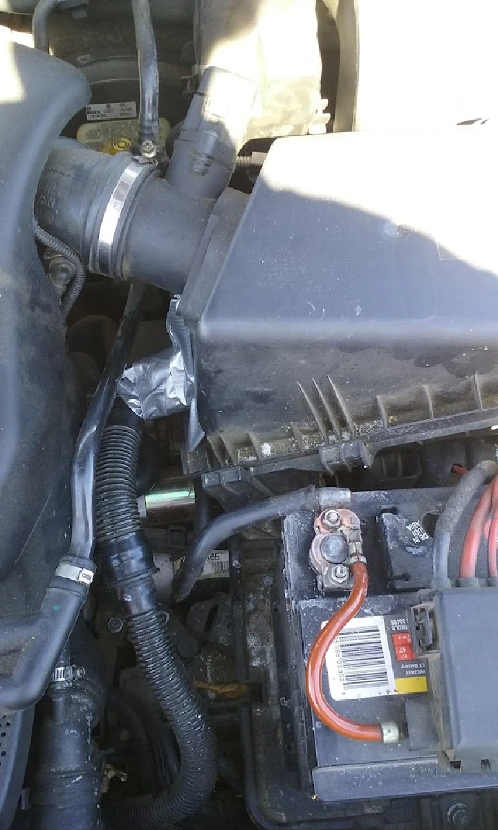 Car engine compartment with battery and cables visible.