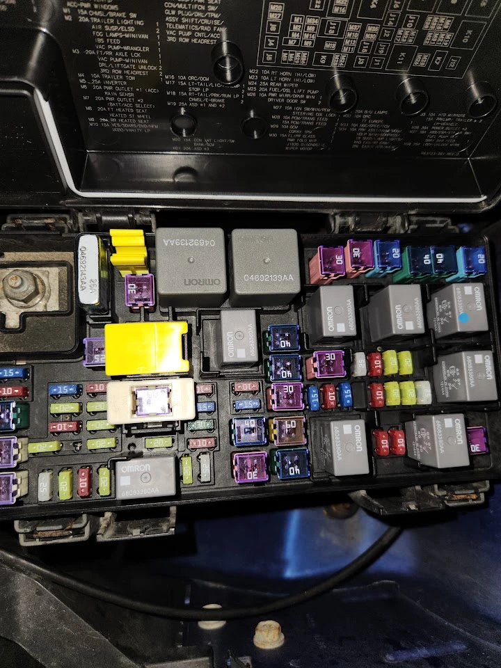 Car fuse box showing various fuses and relays.