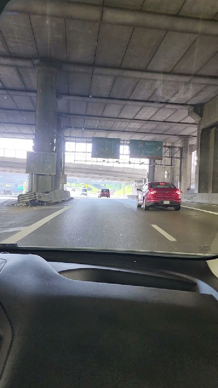 Cars driving under an overpass on a highway.