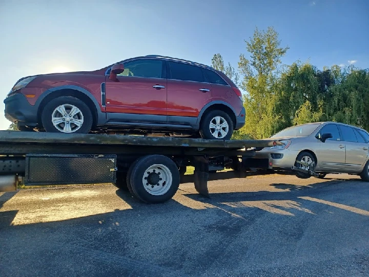 Cars being loaded onto a tow truck for sale.