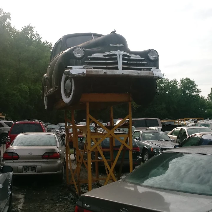 Classic car on a lift in an auto parts yard.