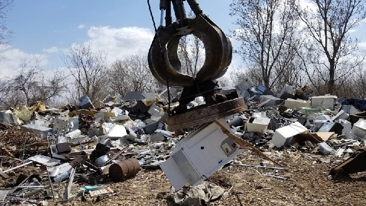 Crane lifting scrap metal at a recycling site.