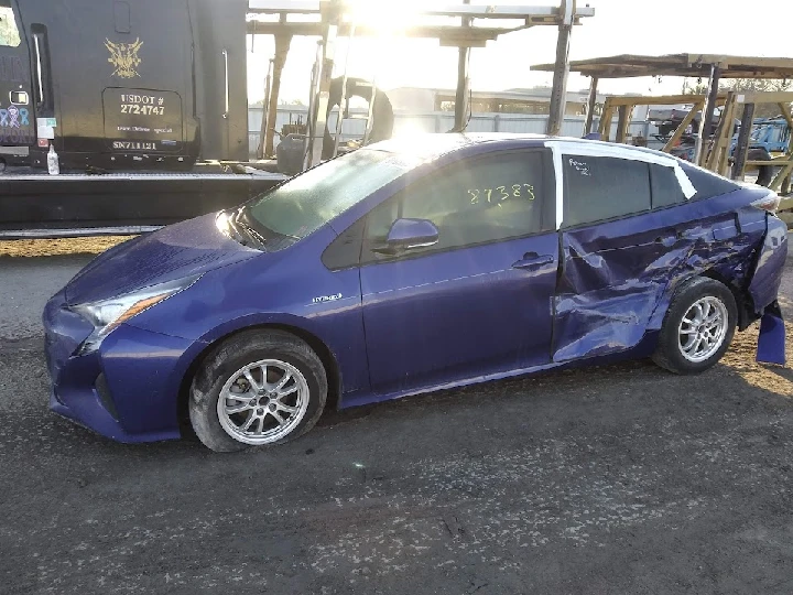 Damaged blue hybrid car at auto recycling yard.