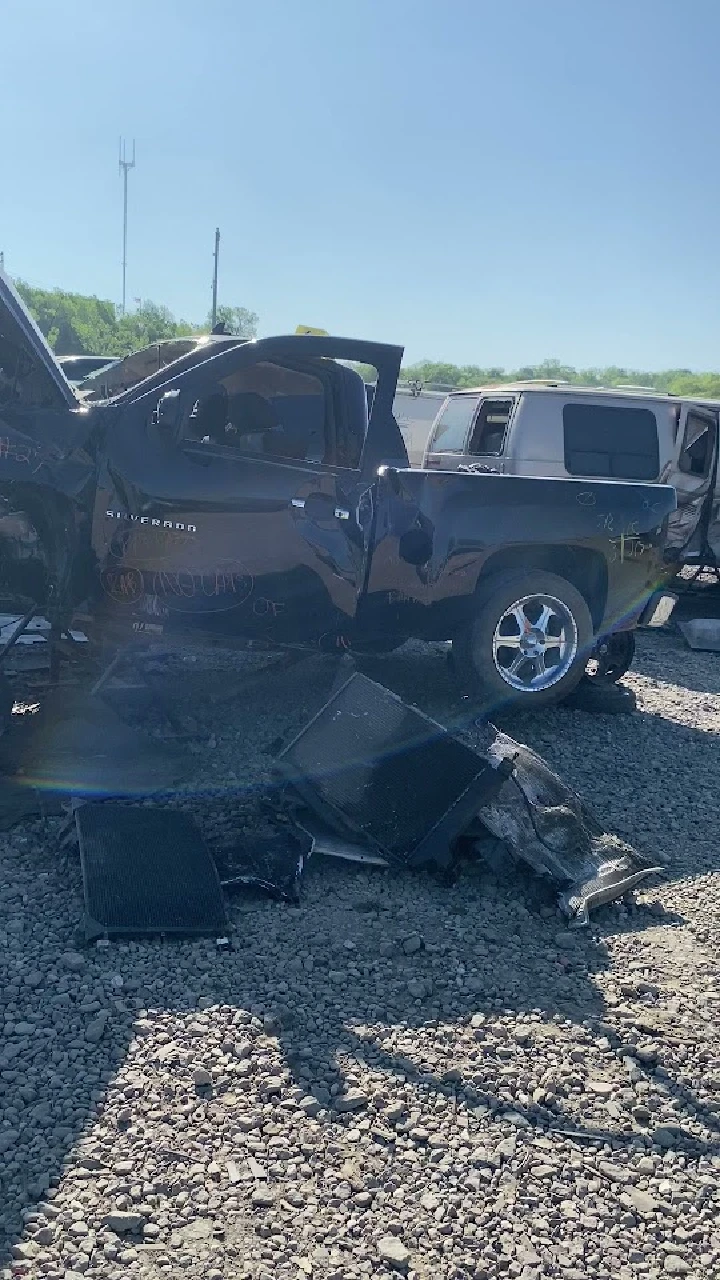 Damaged pickup truck in a junkyard setting.