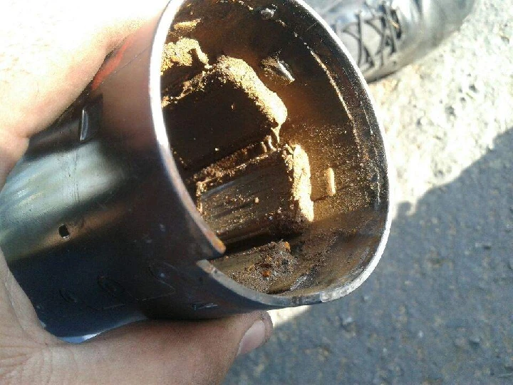 Dirty auto part held in hand, showing wear and rust.