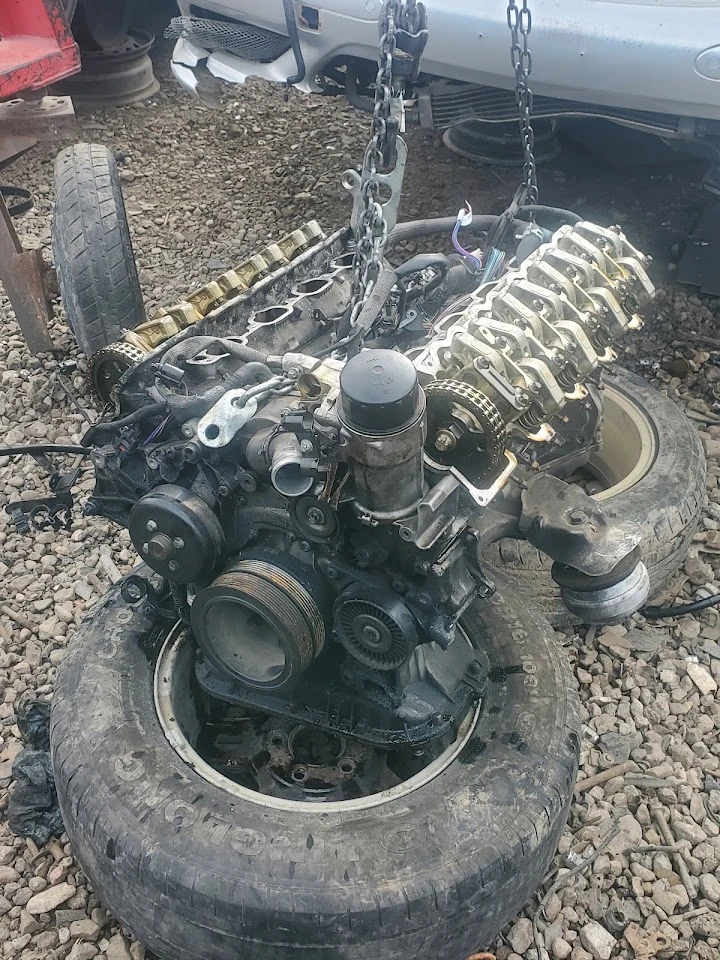 Engine suspended over tires in a salvage yard.