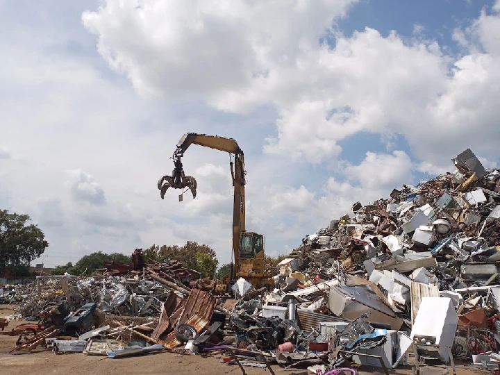 Excavator lifting scrap metal in a junkyard.