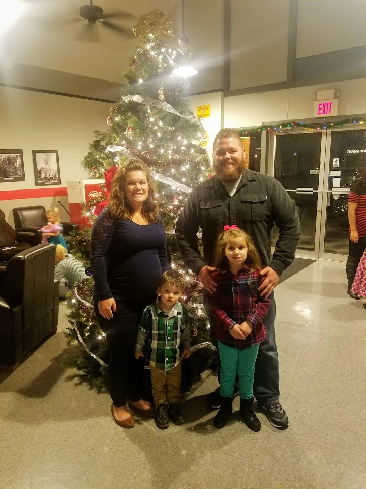 Family posing by a Christmas tree at Fenix Parts.