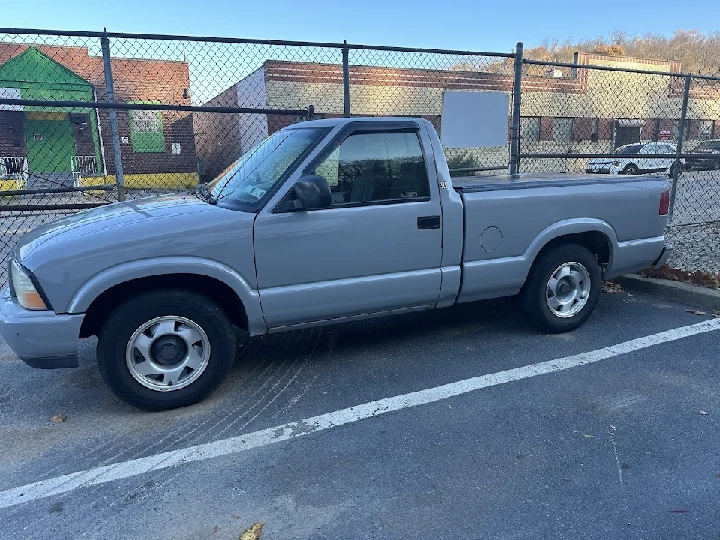 Gray pickup truck parked near a fence.