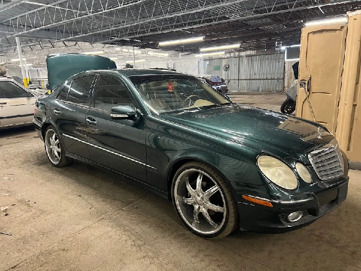 Green sedan in an auto wrecking yard.