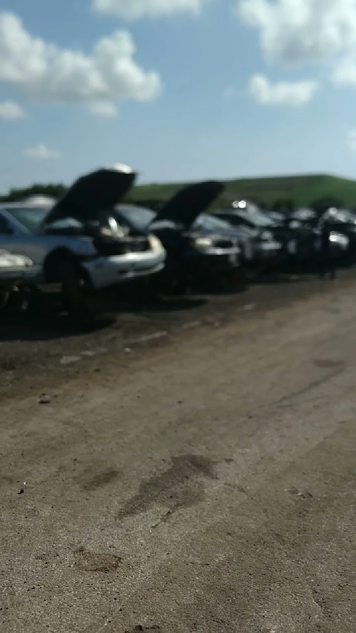 Junkyard scene with cars and open hoods.