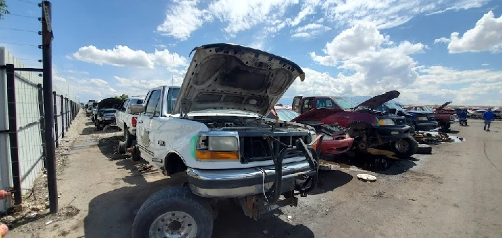 Junkyard scene with damaged vehicles and clear sky.