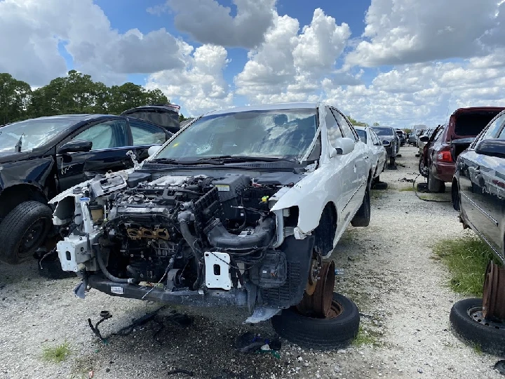 Junkyard scene with dismantled white car.