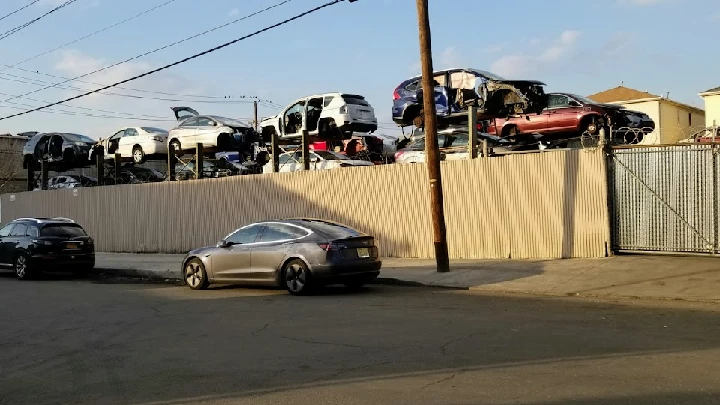 Junkyard with stacked cars and parked vehicles.