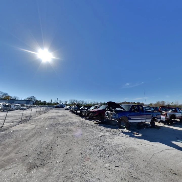 Junkyard with vehicles under a clear blue sky.