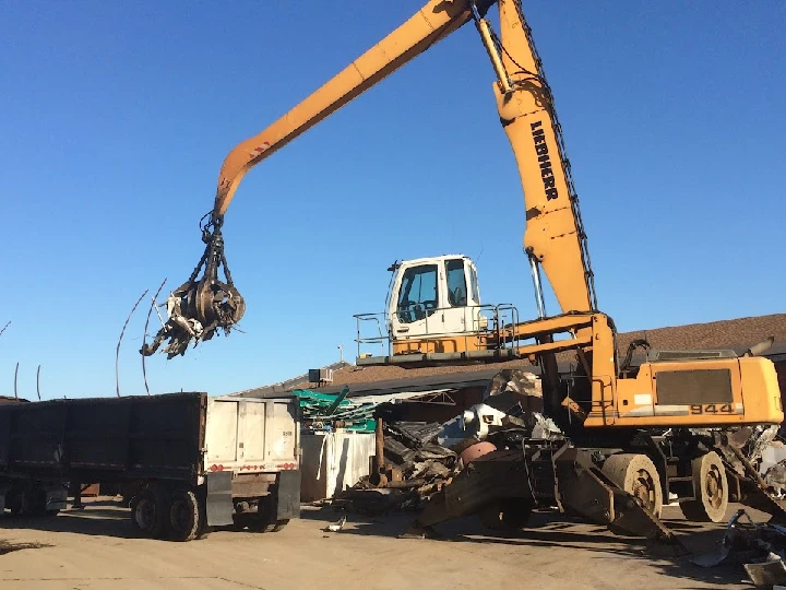 Liebherr crane moving scrap metal at a junkyard.