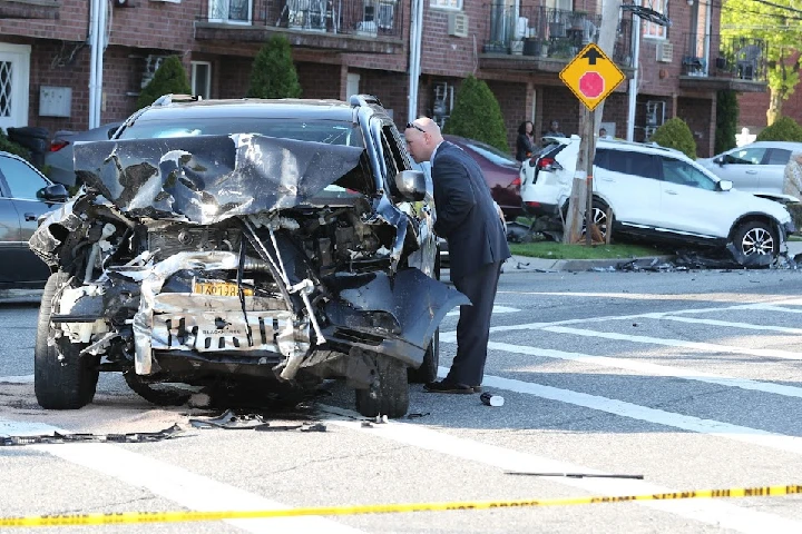 Man examines a heavily damaged car at an accident site.