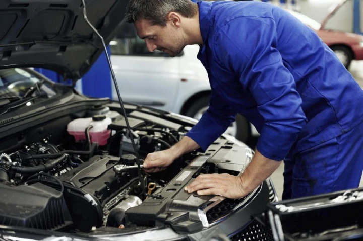 Mechanic working on a car engine in the shop.