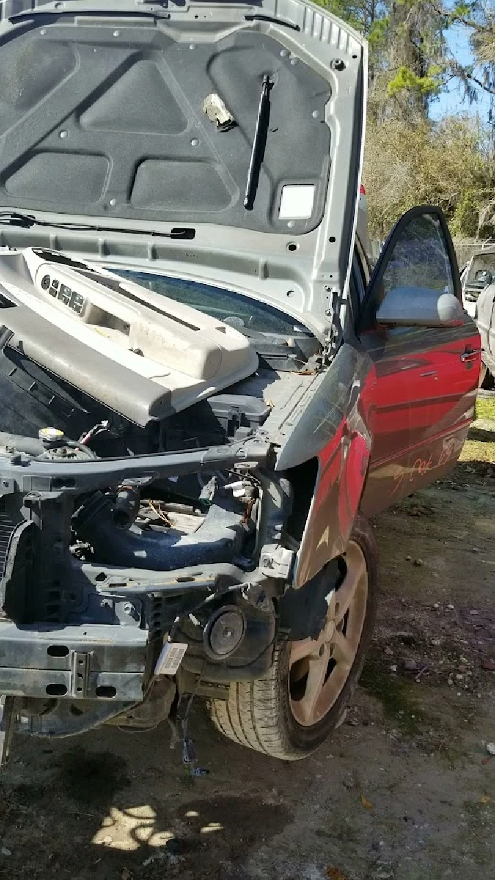 Open hood of a dismantled car at a salvage yard.