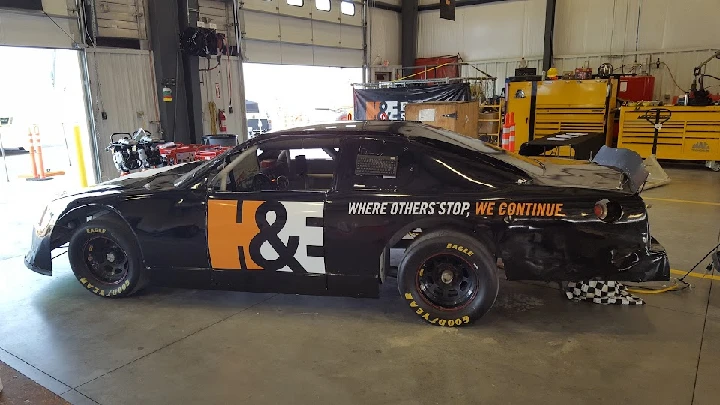 Race car in a garage with branding and equipment.