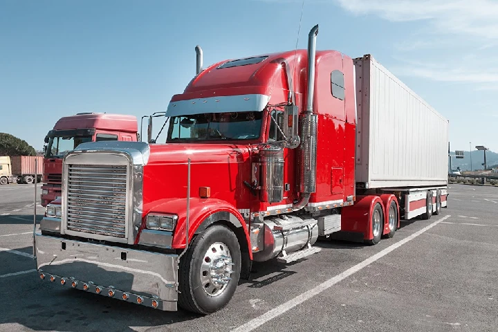 Red semi-truck parked in a sunny lot.