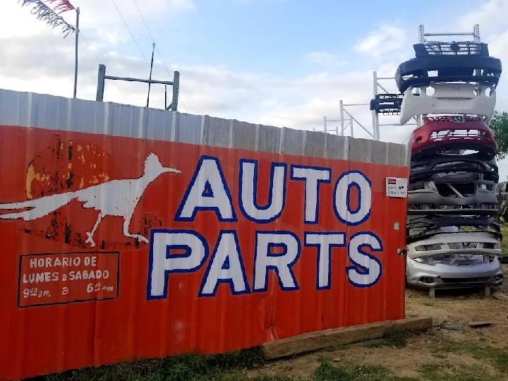 Sign for Paisano Used Auto Parts with stacked bumpers.