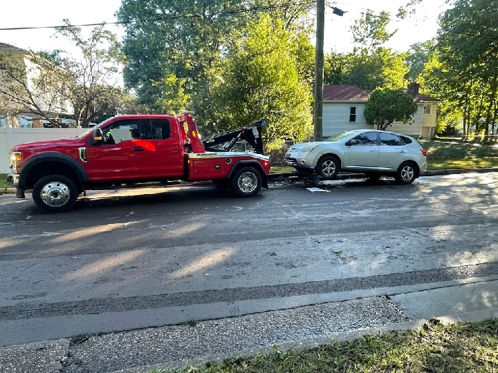 Tow truck transporting a car on a suburban street.