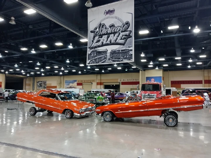 Two custom orange lowriders on display indoors.