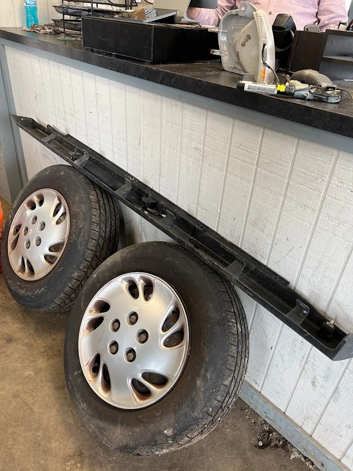 Two used tires and a car part on a counter.