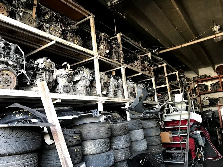 Used auto parts stacked in a warehouse setting.