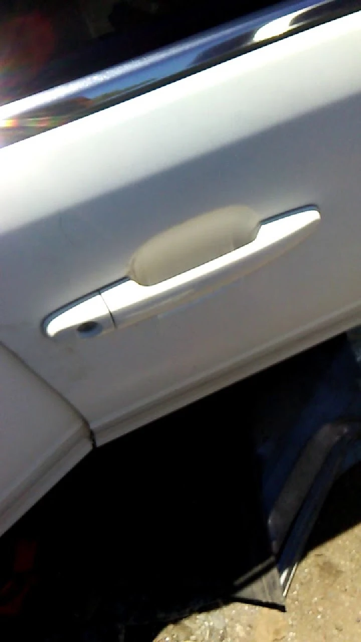 White car door with silver handle, partially open.