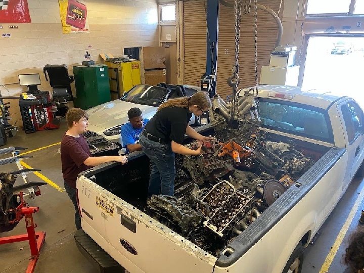 Workers handling auto parts in a garage setting.