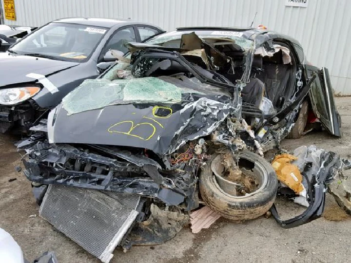 Wrecked car with severe damage at an auto yard.