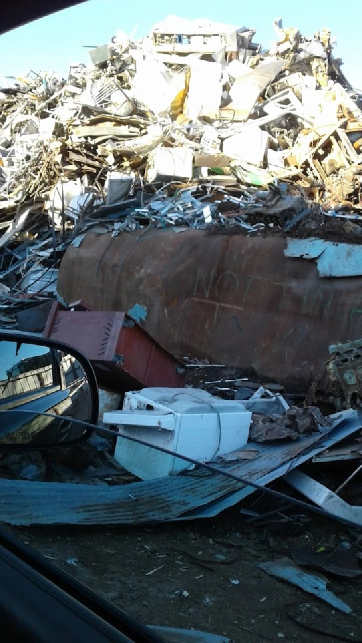 A pile of scrap metal and appliances at a recycling yard.