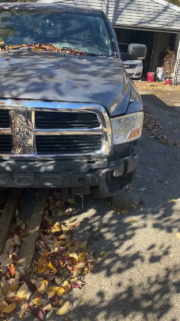 Abandoned truck with leaves, parked in a yard.