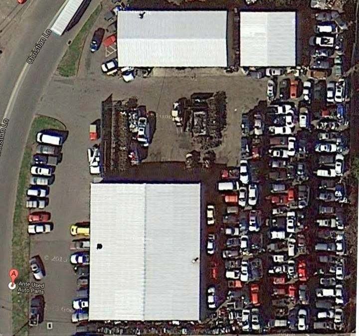 Arite Used Auto Parts yard with numerous parked cars.