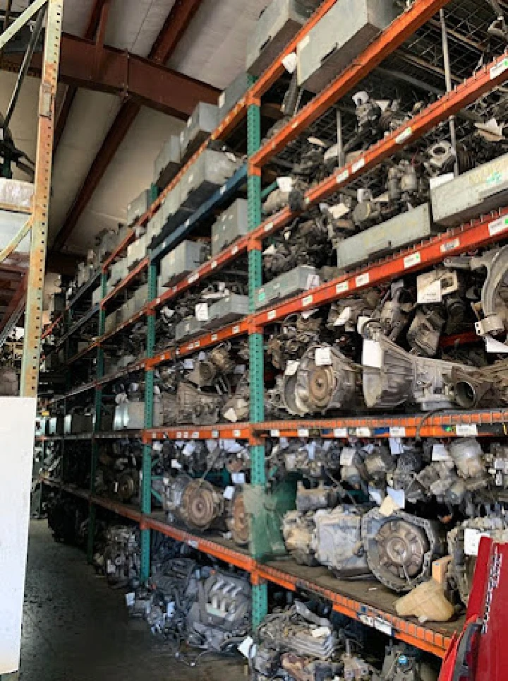 Auto parts stacked on shelves at a dismantling site.