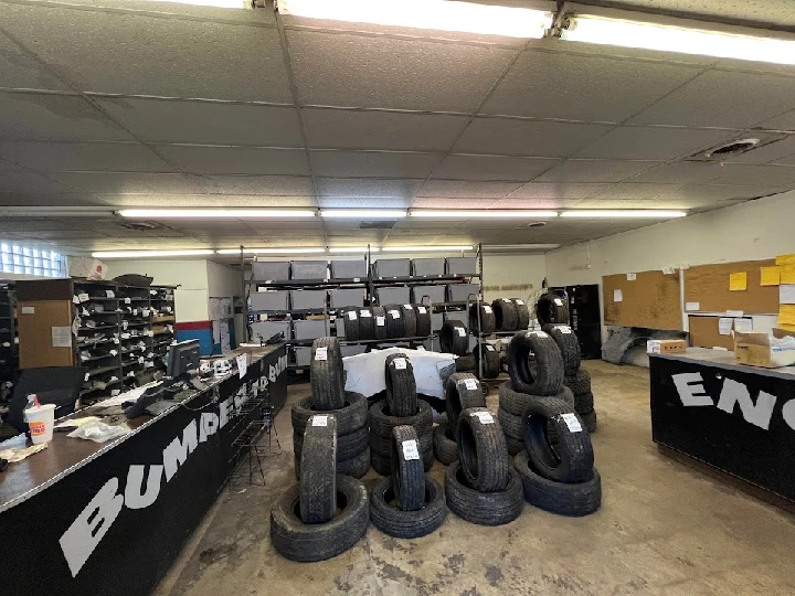 Auto recycler interior with stacked tires and desks.