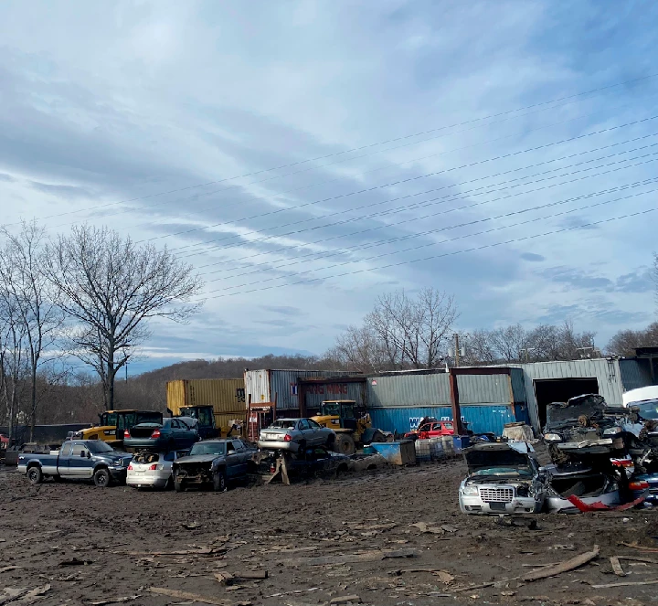 Auto salvage yard with stacked vehicles and containers.