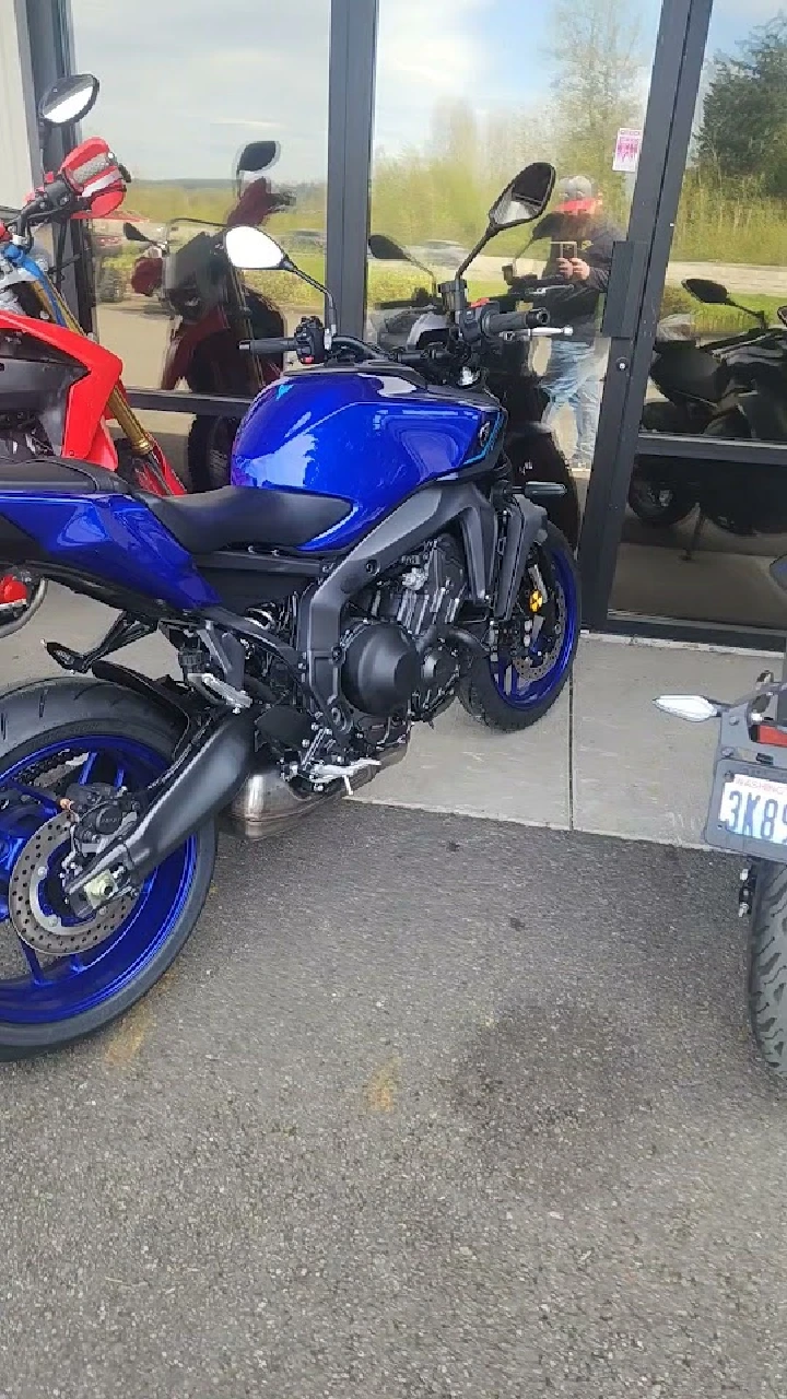 Blue motorcycle parked outside the shop.