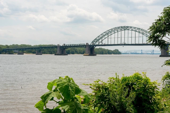 Bridge over water with lush greenery in foreground.