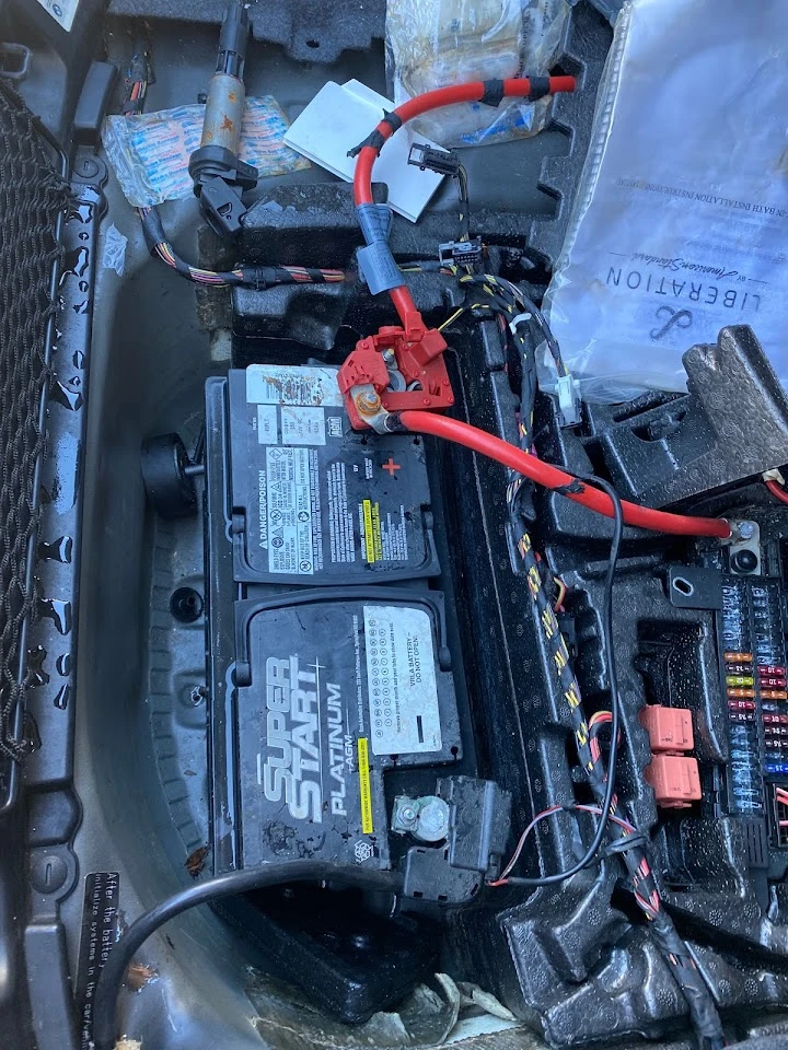 Car battery and wiring in a vehicle's engine bay.