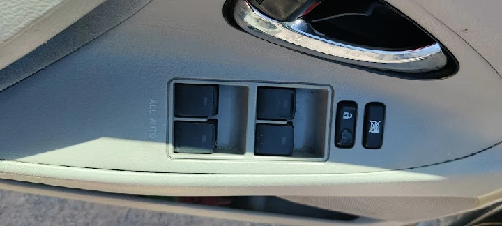 Car window control panel in beige interior.